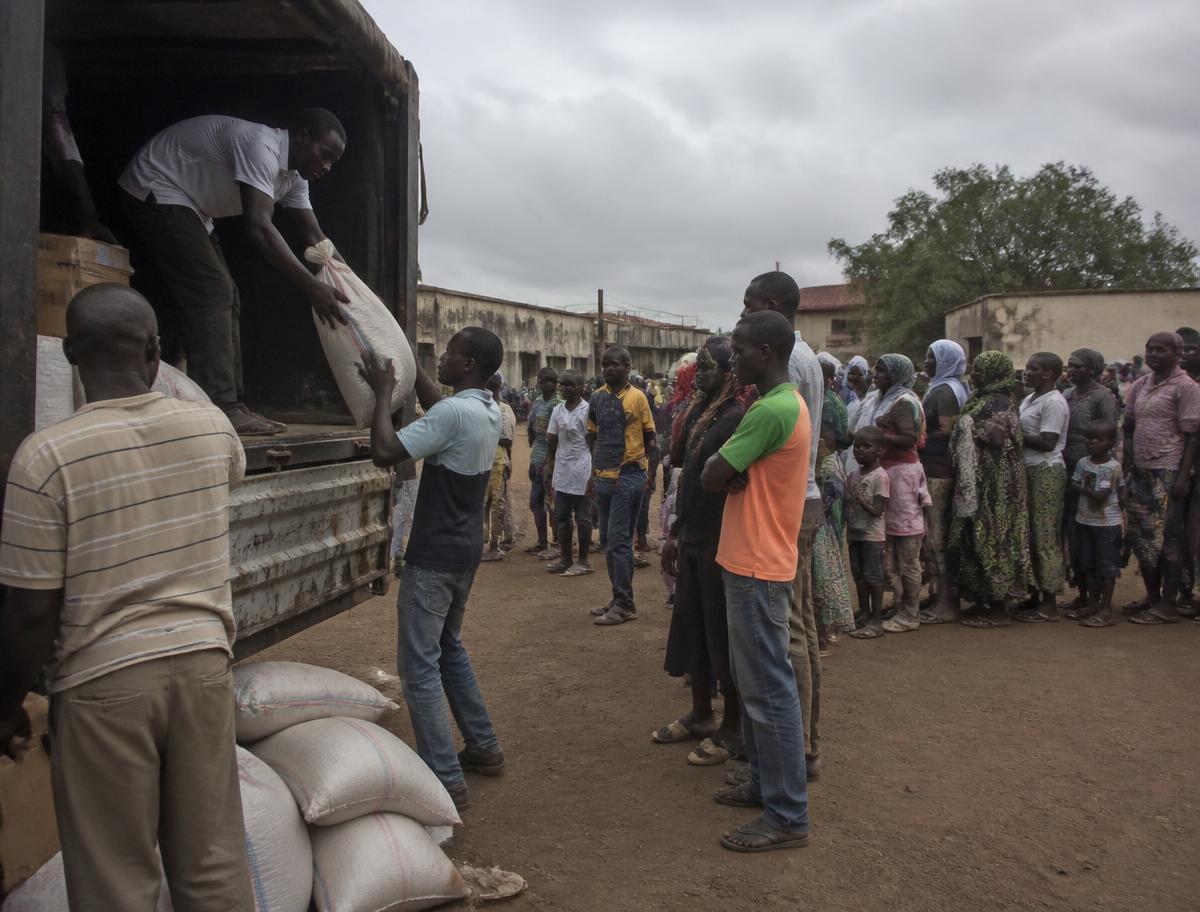 Volunteers unloading sacks and boxes of relief supplies from a truck as people queue